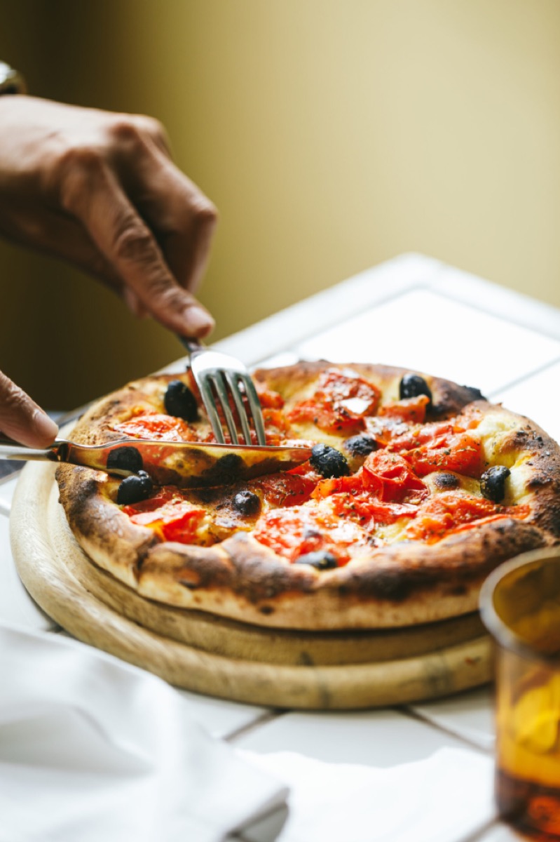 Wood-fired pizza with olives being served